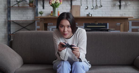 Energetic Young Asian Woman Using Jostick Wireless Gamepad Controllr Playing Modern Video Games on