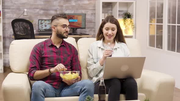 Happy Couple on the Couch Eating Chips