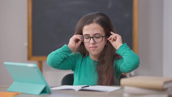 Portrait of Genius Concentrated Caucasian Young Woman Putting on Eyeglasses Writing with Pen Looking