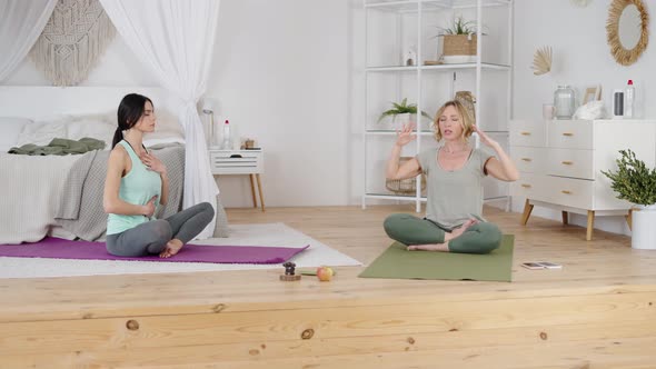 Relaxed Woman Practicing Breathing Exercise with Yoga Instructor