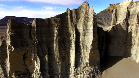 Flying over cliff spires revealing desert landscape covered in tire tracks