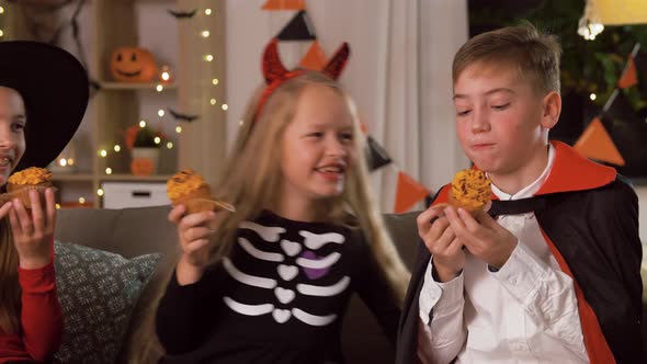 Kids in Halloween Costumes Eating Cupcakes at Home