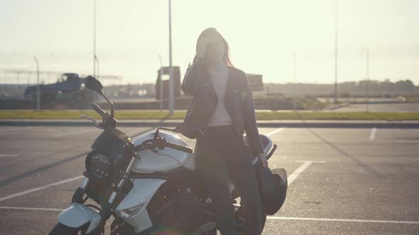 Beautiful Young Redhaired Woman Motorcyclist in a Leather Jacket on Bike