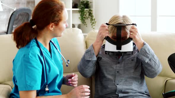 Female Nurse Helping Senior Woman To Experience Virtual Reality