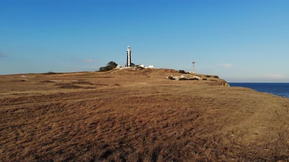 Aerial View of an Unknown Lighthouse with Black and White Edges on the Peninsula's Promontory