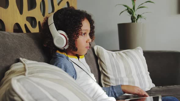 Side view of Caucasian boy with headset playing game on digital tablet in lobby at hospital 4k