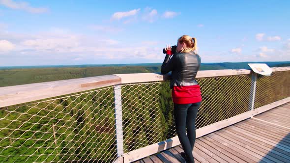 Zoom in on woman tourist taking pictures at a viewpoint in Mt. Sommerberg, Black Forest, Germany