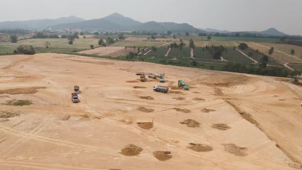 Preparation process on Construction site, Trucks and Excavators clearing the field, Aerial Orbiting