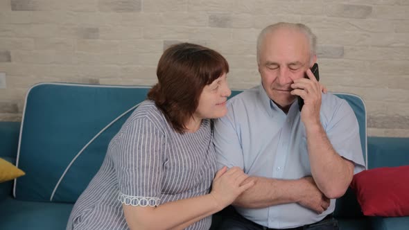 Man Is Talking on Phone with Son and His Wife Is Trying To Listen the Discussion