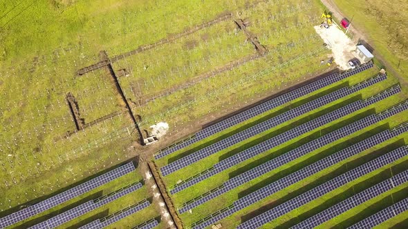 Aerial view of solar power plant under construction on green field. Assembling