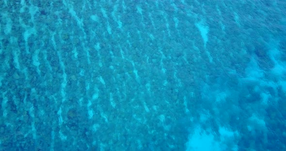 Tropical overhead island view of a sandy white paradise beach and aqua blue water background in colo