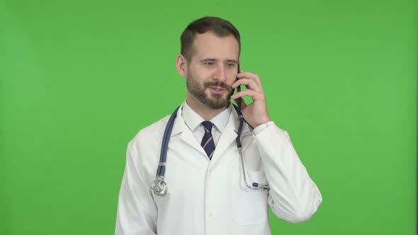 Young Male Doctor Speaking on the Phone Against Chroma Key