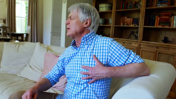 Senior man suffering from chest pain in living room