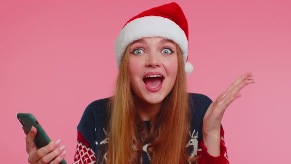 Woman in Stylish Christmas Sweater Looking Smartphone Display Sincerely Rejoicing Win Success Luck