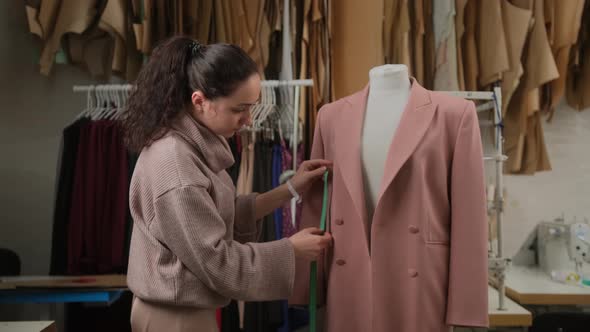 female tailoring fashion designer measuring suit jackets on mannequin dummy in workshop