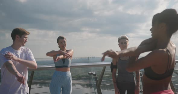 Young Athletes Do Arm Stretching After Latin Lady on Bridge