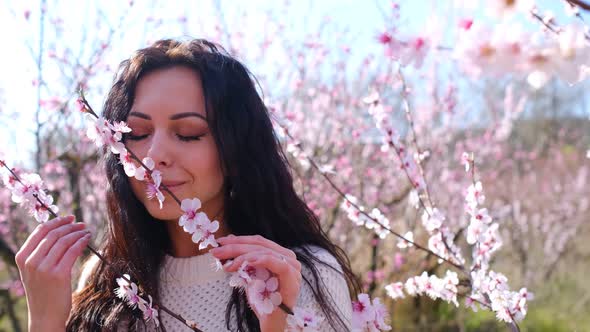 Happy Woman Having Fun in an Orchard with Pink Blossom Peach Flower Trees