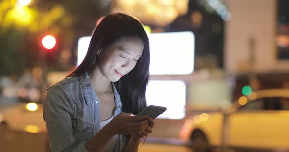 Woman using cellphone at night in Hong Kong 