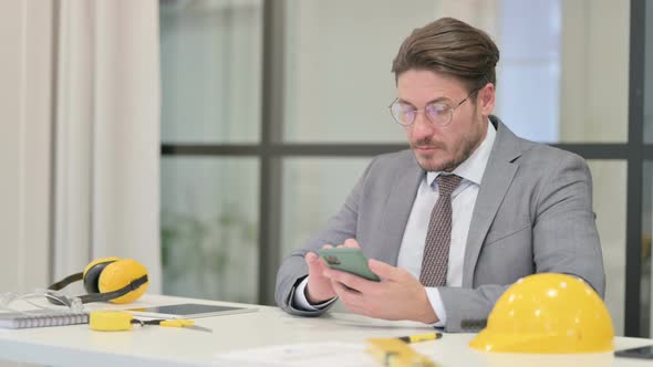 Attractive Middle Aged Engineer using Smartphone in Office