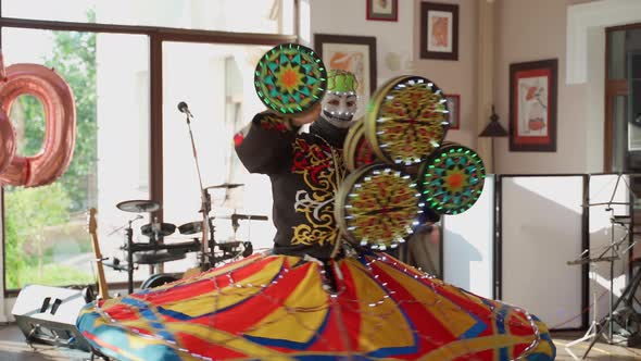 Unrecognizable person dancing national dance tanura indoors. Man in mask show performance at event