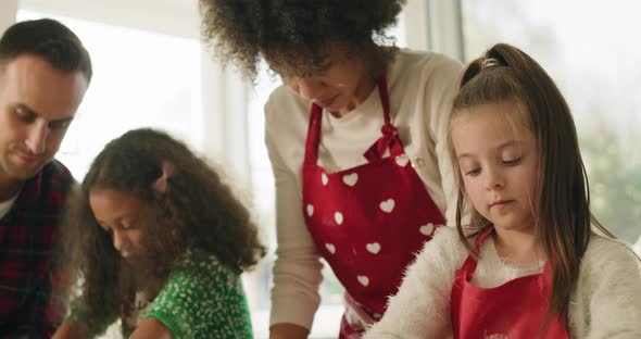 Handheld view of children baking cookies with help of parents