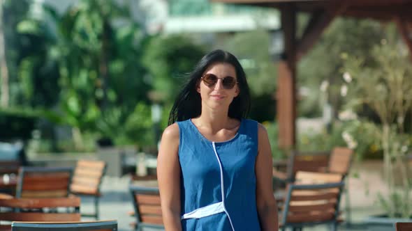 Smiling Casual Brunette Girl in Sunglasses Walking at Luxury Resort Area Playing Hair Medium Shot