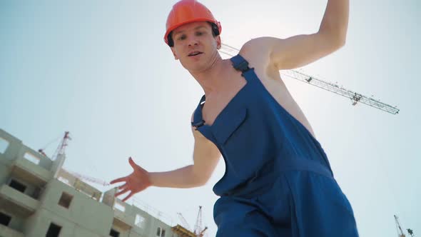 Happy Caucasian Man Builder in Hard Hat Dancing. Worker Funny Moves Background Construction Site.