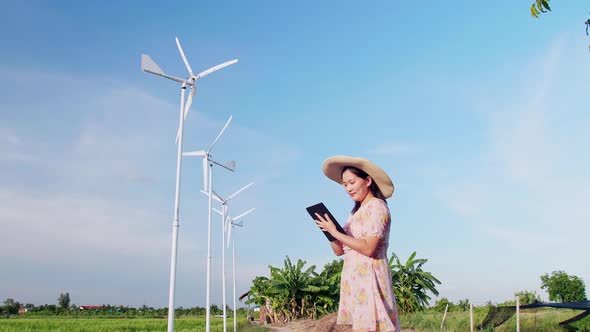 Woman using digital tablet near wind power generation turbines.