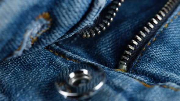 Denim. Blue jeans with metal zip, close up. Sliding shot