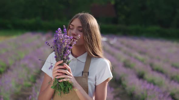 Smiling Girl Smelling Lavender Flowers in Field