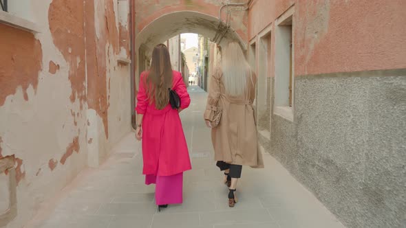 Girl Friends Walk Along Venetian Street Between Old Houses