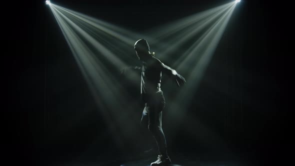 Dark Silhouette Guy Dancing in a Street Style Break Dance. Black Background with Neon Spotlights and