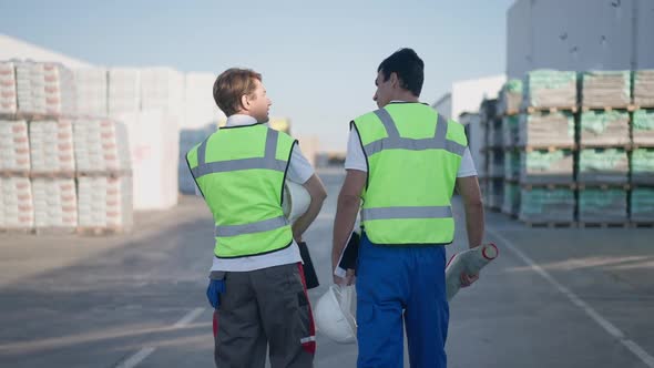 Two Confident Professional Engineers Walking in Slow Motion at Outdoors Warehouse Talking