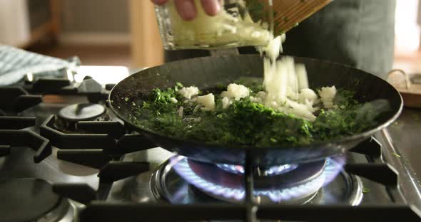 Woman steaming parsley and onions for Maultaschen filling