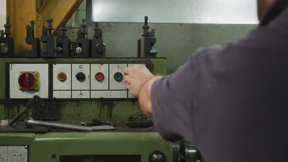 Caucasian male factory worker pushing a button and turning on the machine