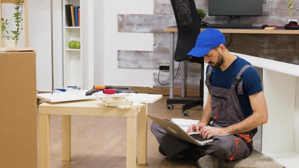 Furniture Assembly Worker Uses Laptop To Consult Instructions