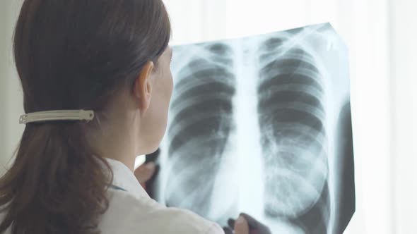 Caucasian Doctor Examining Lungs X-ray. Shooting Over Shoulder of Serious Professional Looking at