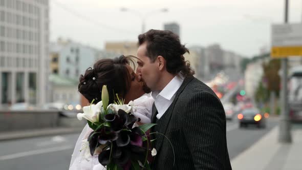 Happy Just Married Pair is Kissing on City Street in Wedding Day