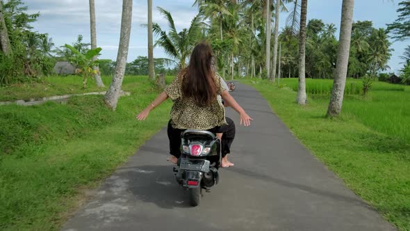 Happy couple tripping by motorcycle on tropical road at sunset time. Outdoor shot of young couple