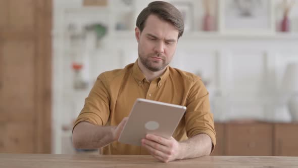 Young Man using Tablet while Sitting in Office