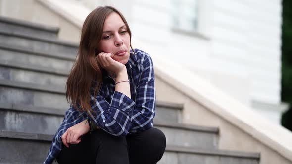 Young Pretty Woman Shows Her Tongue Sitting on Stairs of Manor