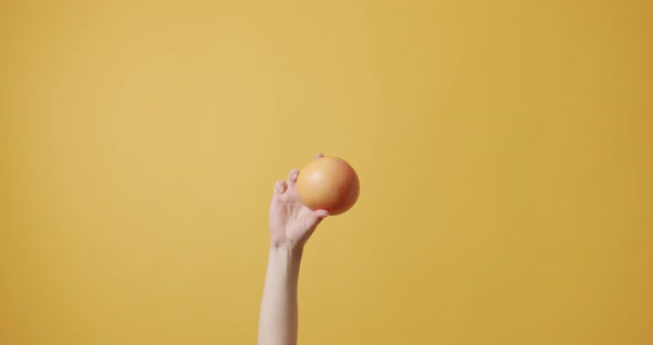 The Girl's Hand Holding an Orange Fruit and Shows the Symbol Okay