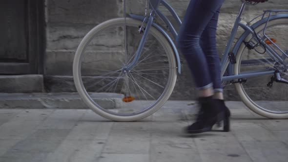 Girl In Black Heeled Boots Pushing Her Bicycle In The Sidewalk