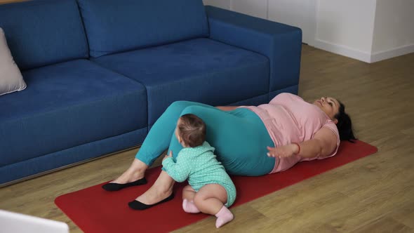 Overweighted Woman Doing Abdominal Exercises While Her Baby Playing Next to Her