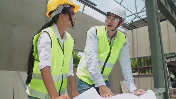 Asian colleague workers people wearing protective safety helmet and glasses onsite of architecture.