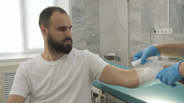 Doctor applying bandage on the hand of the patient. Visiting traumatologist. Bandage hand.