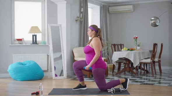 Side View of Young Obese Caucasian Woman Exercising at Home Indoors