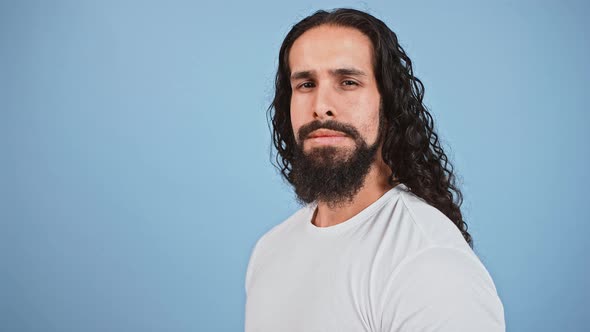 Studio Shot of Young Serious Man Turning From Profile to Camera and Happily Smiling