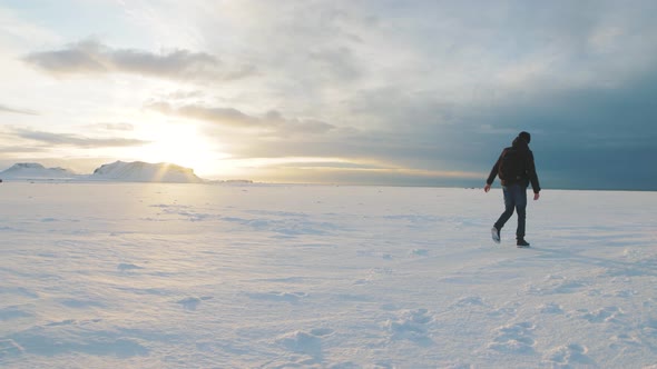 Man Traveler Walking on Snow Desert in Iceland