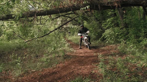 Slowmo of Motorcyclist Riding in Forest